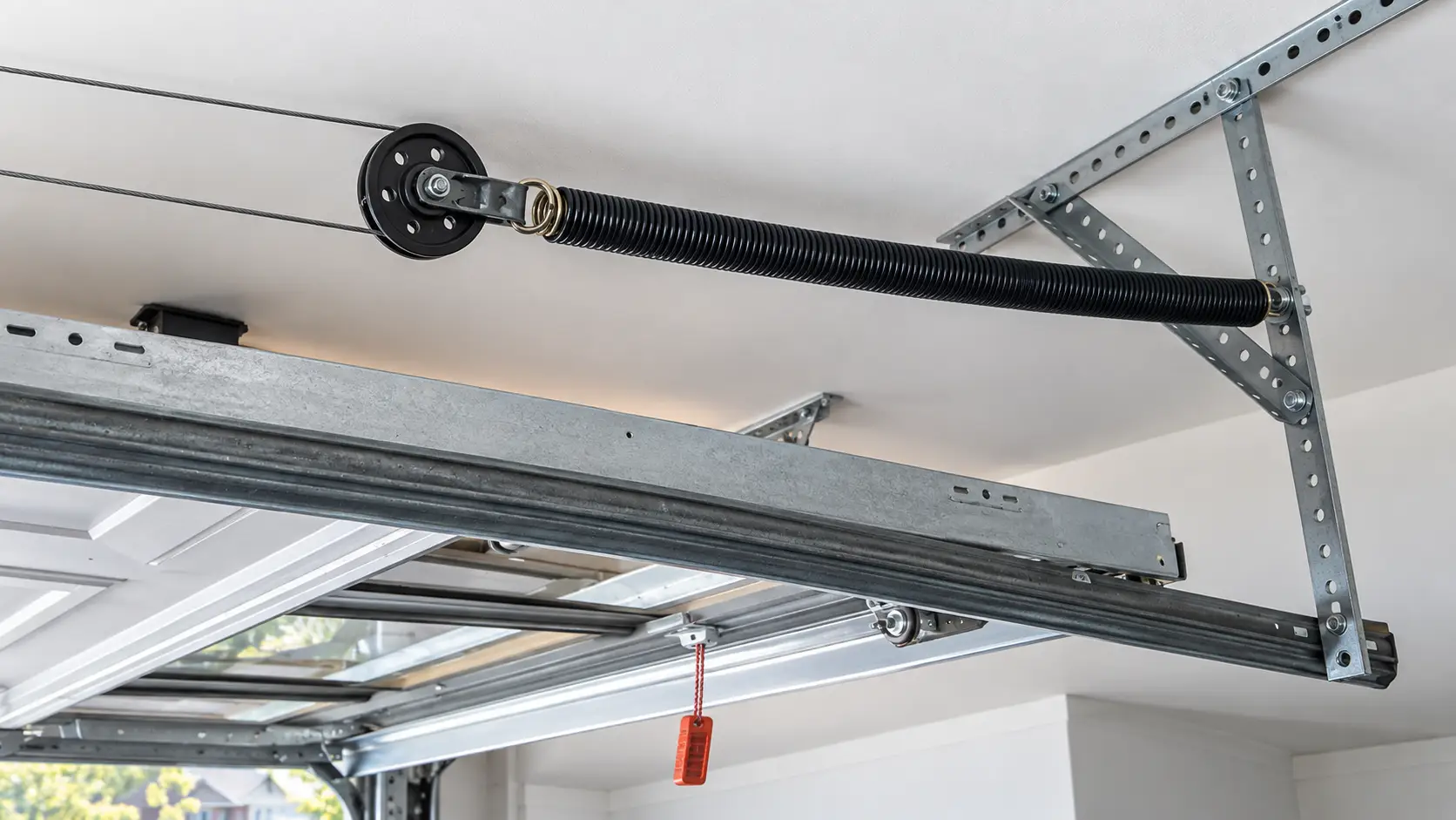 Commercial garage door lift cables and cable drums supporting an overhead door