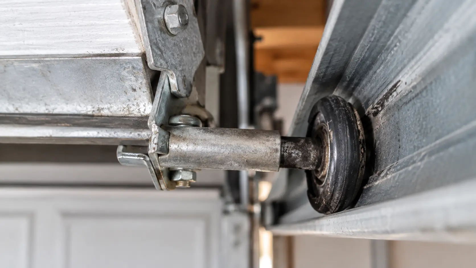 Close-up of a worn garage door roller bearing and steel track